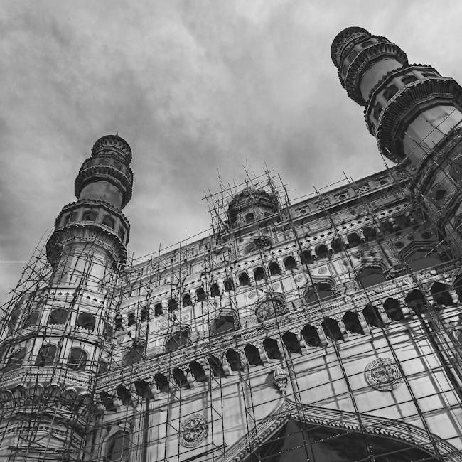 Black and white image capturing the Charminar under restoration with scaffolding.